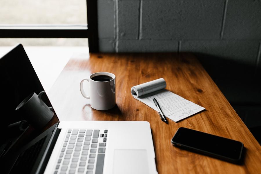 Desk with computer, tea cup, phone and notepad